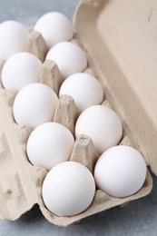 Photo of Raw chicken eggs in egg carton on grey table, closeup