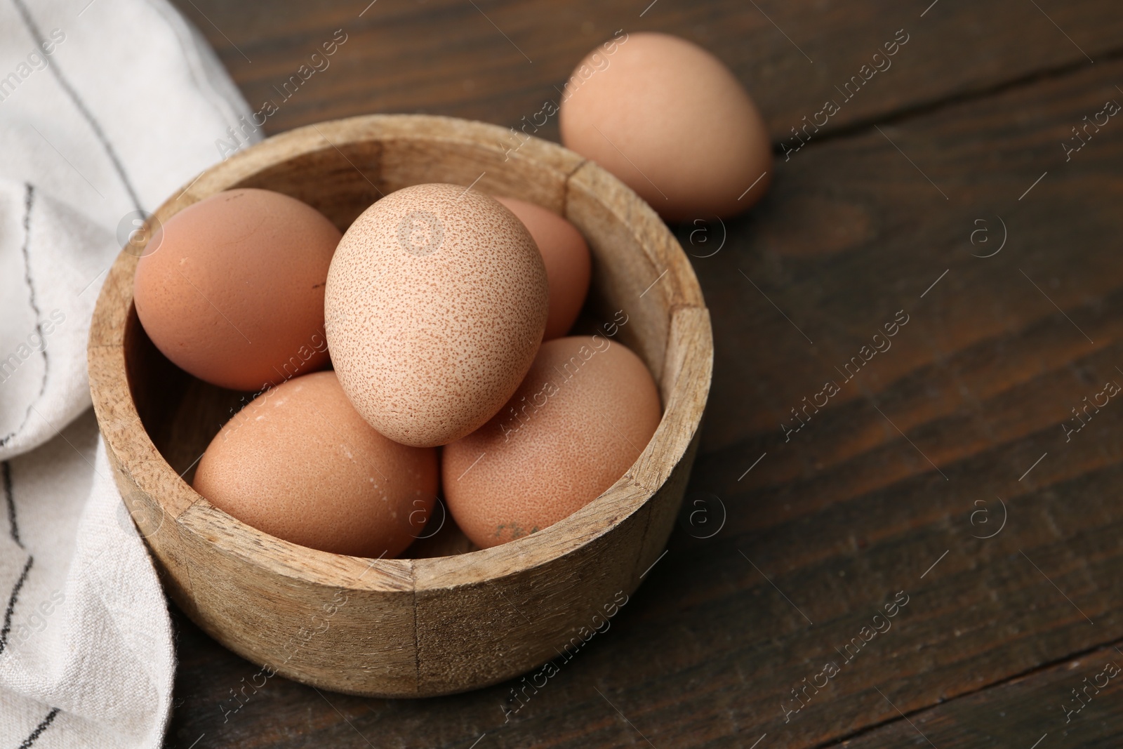 Photo of Raw chicken eggs in bowl on wooden table, closeup. Space for text