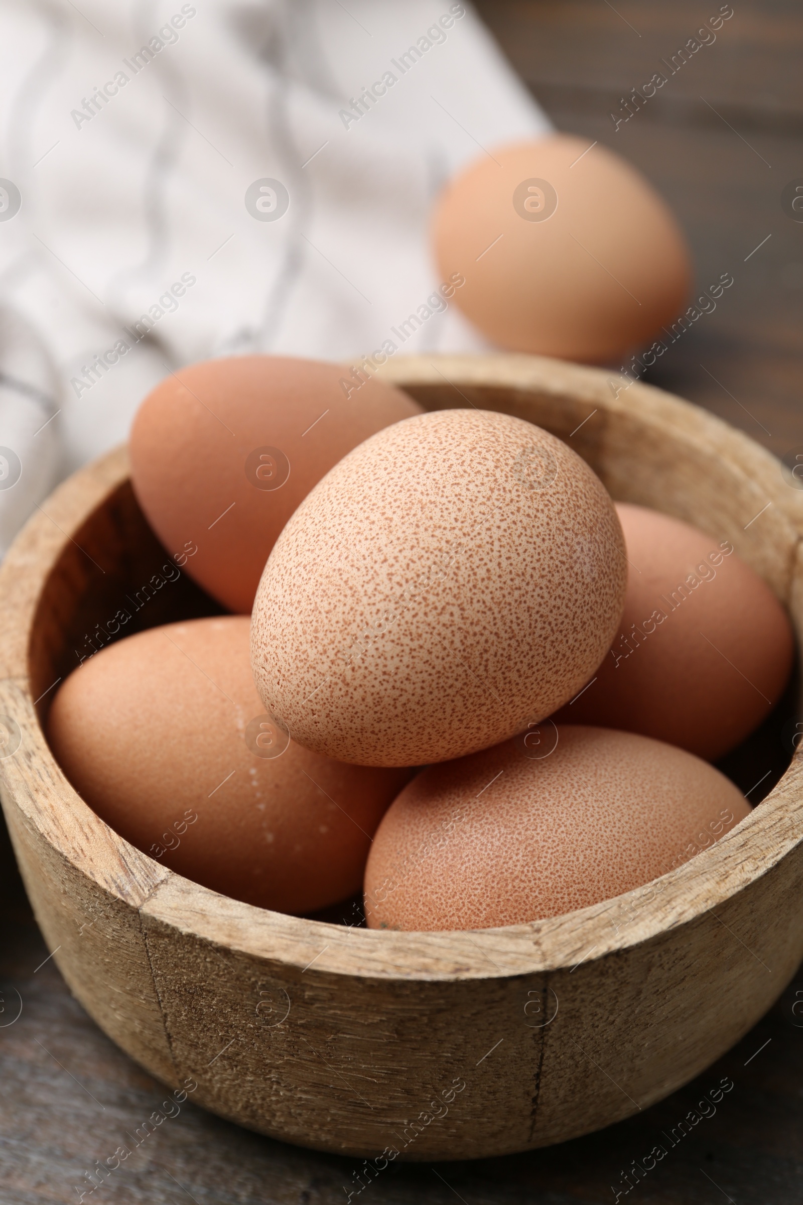 Photo of Raw chicken eggs in bowl on wooden table, closeup