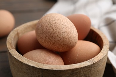 Photo of Raw chicken eggs in bowl on wooden table, closeup
