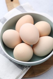 Photo of Raw chicken eggs in bowl on white table, closeup