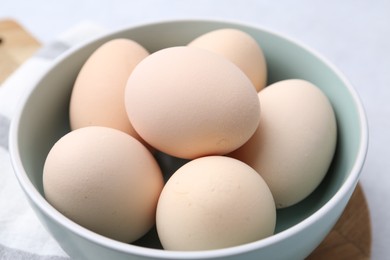 Photo of Raw chicken eggs in bowl on white table, closeup