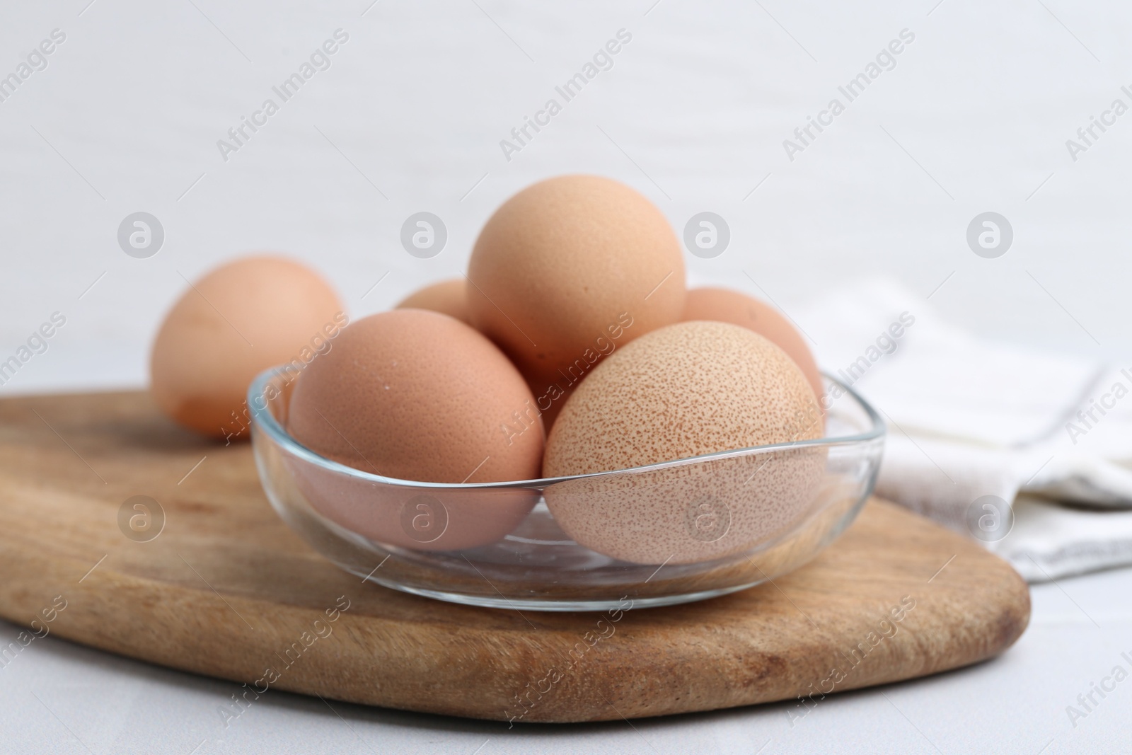 Photo of Raw chicken eggs in bowl on white table, closeup