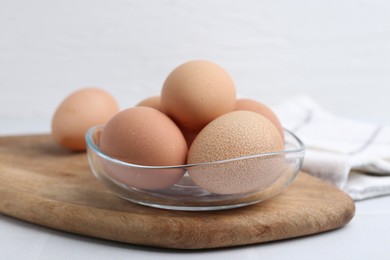 Photo of Raw chicken eggs in bowl on white table, closeup