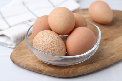 Photo of Raw chicken eggs in bowl on white table, closeup