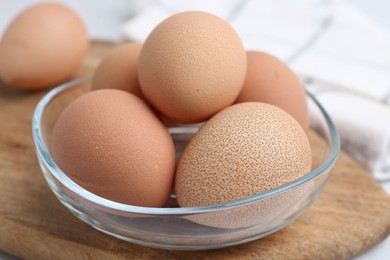 Photo of Raw chicken eggs in bowl on white table, closeup