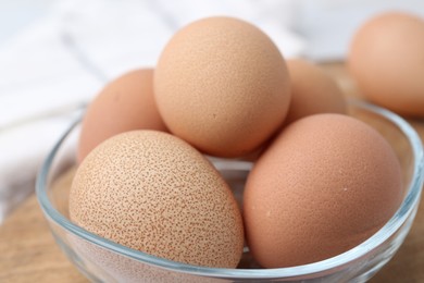 Photo of Raw chicken eggs in bowl on table, closeup