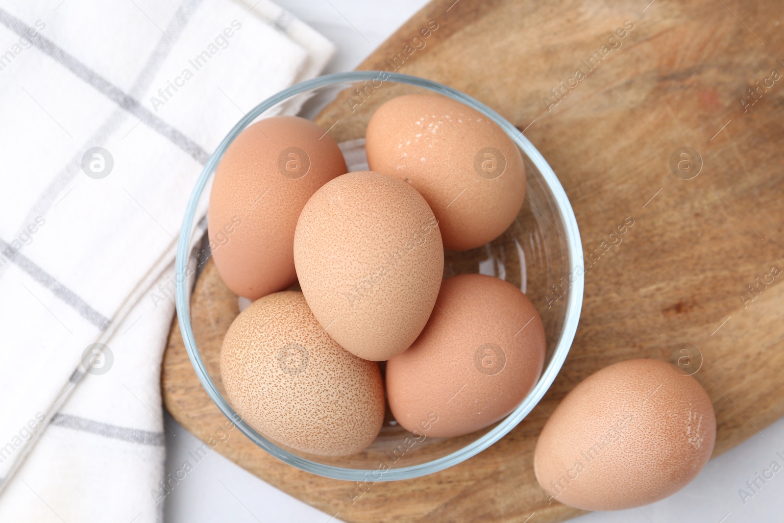 Photo of Raw chicken eggs in bowl on white table, top view