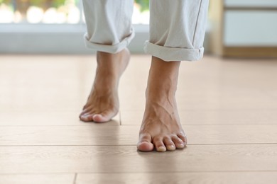 Image of Woman walking barefoot on warm floor indoors, closeup. Underfloor heating