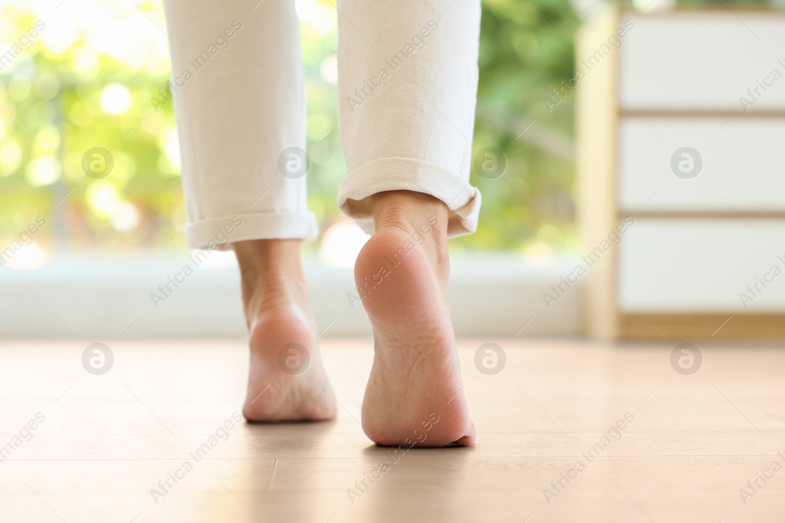Image of Woman walking barefoot on warm floor indoors, closeup. Underfloor heating