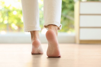 Image of Woman walking barefoot on warm floor indoors, closeup. Underfloor heating