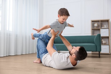 Image of Father and son feeling comfortable to have fun together barefoot on warm floor at home. Underfloor heating