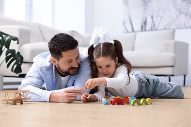 Image of Father and daughter feeling comfortable to play together on warm floor at home. Underfloor heating