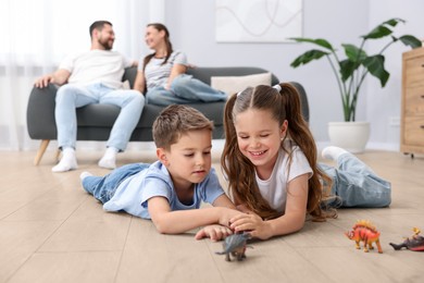 Image of Children feeling comfortable on warm floor, while their parents sitting on sofa at home. Underfloor heating