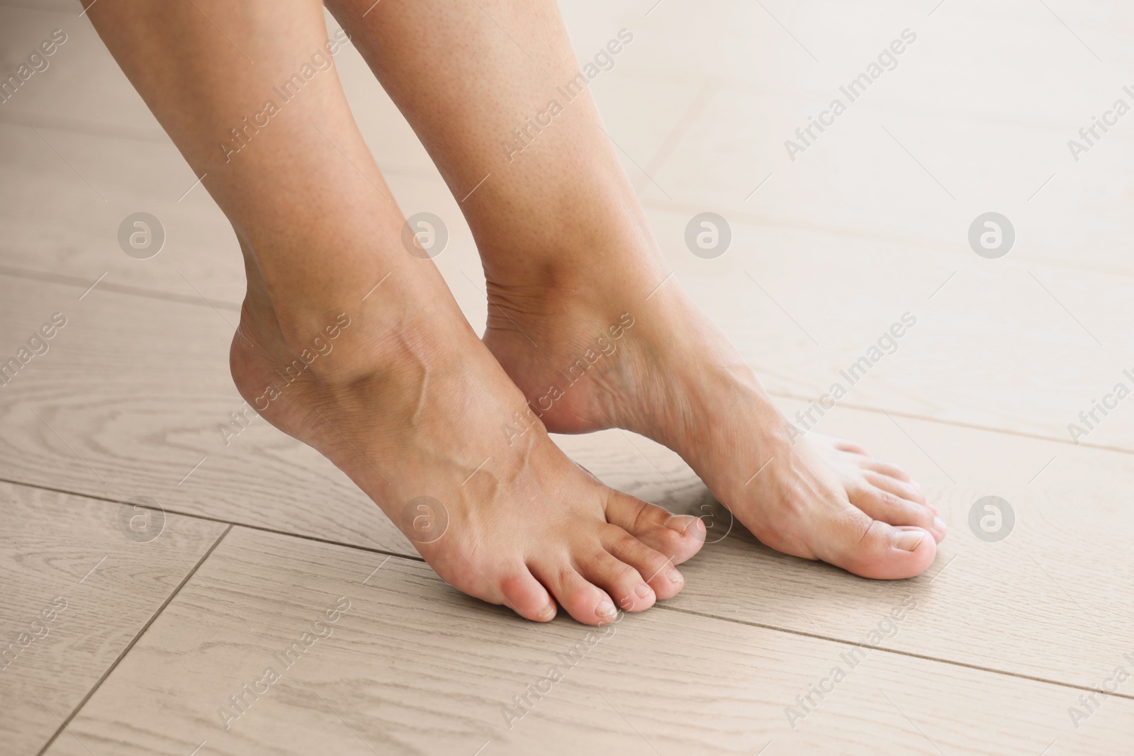 Image of Barefoot woman feeling comfortable on warm floor at home, closeup. Underfloor heating