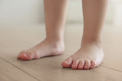 Image of Child standing barefoot on warm floor indoors, closeup. Underfloor heating