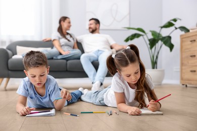 Image of Children feeling comfortable on warm floor, while their parents sitting on sofa at home. Underfloor heating