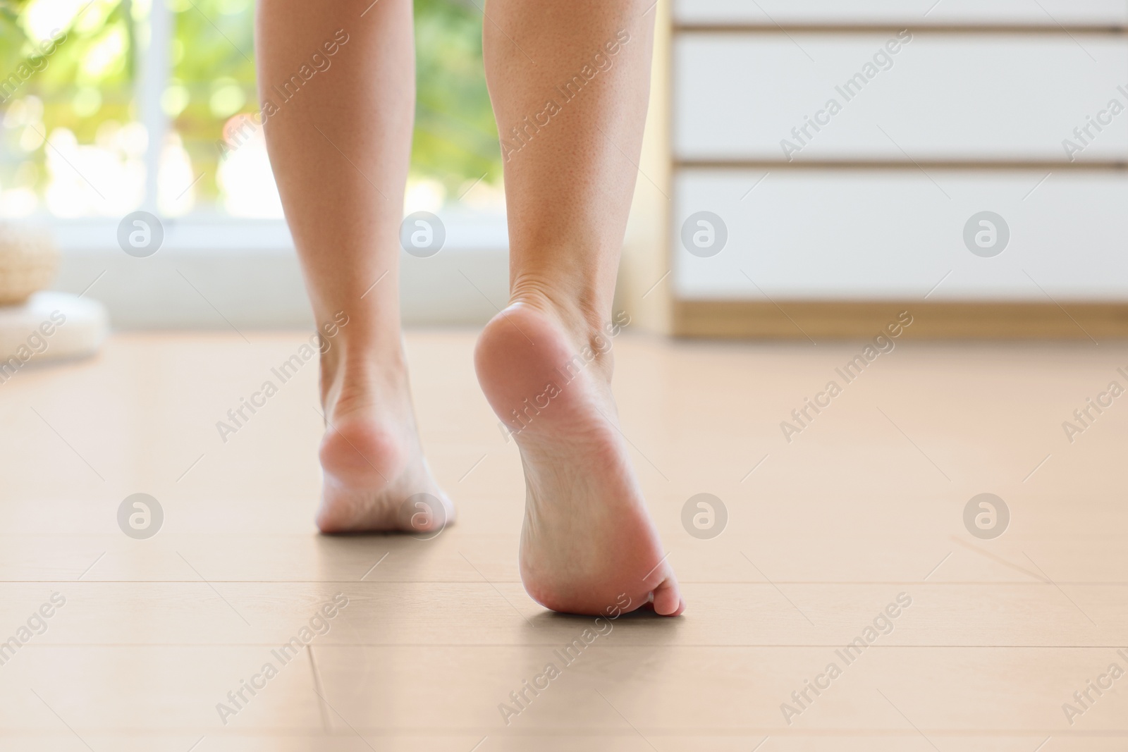 Image of Woman walking barefoot on warm floor indoors, closeup. Underfloor heating