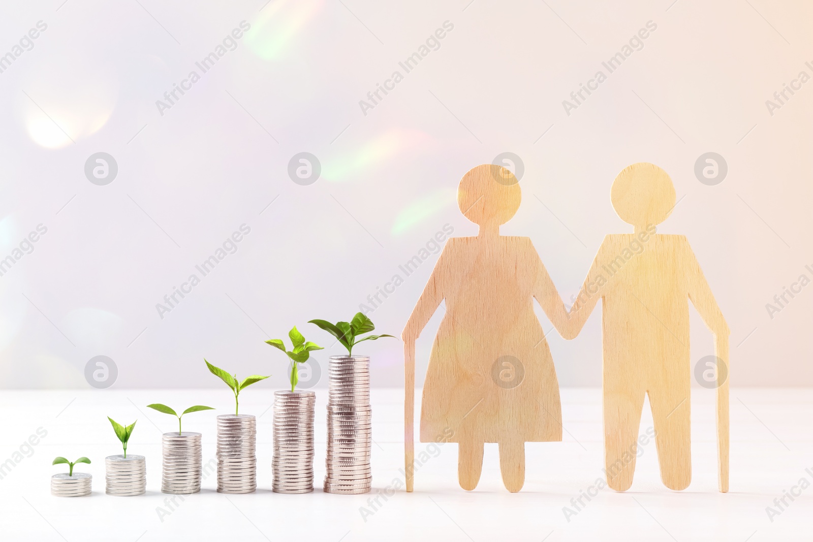 Retirement savings. Stacked coins with green sprouts on tops and wooden figure of two old people on table Image of Retirement savings. Stacked coins with green sprouts on tops and wooden figure of two old people on table