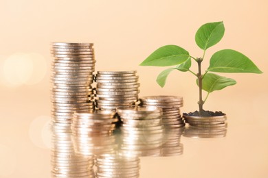 Image of Savings concept. Stacked coins and green sprout on beige background