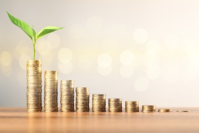 Image of Savings concept. Coin stacks and green sprout on higher one against light background, bokeh effect