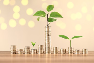 Image of Savings concept. Stacked coins and green sprouts against beige background, bokeh effect