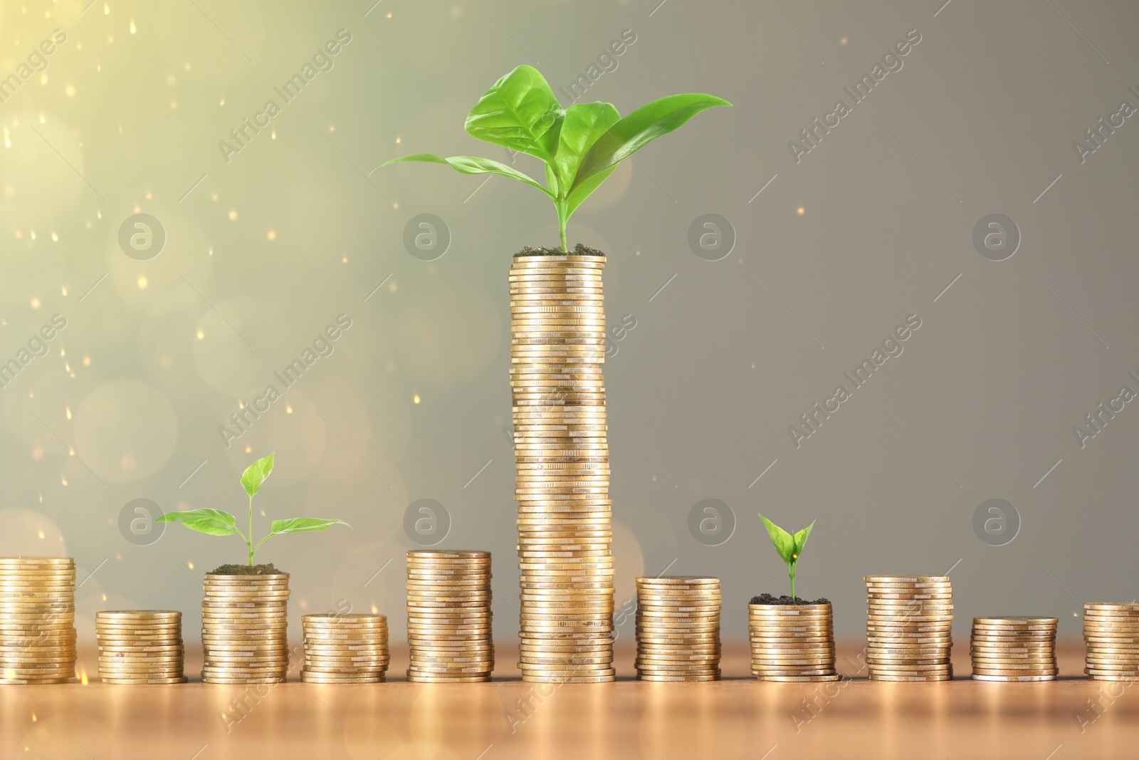 Savings concept. Stacked coins and green sprouts against grey background Image of Savings concept. Stacked coins and green sprouts against grey background