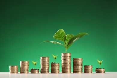 Image of Savings concept. Stacked coins with sprouts on table against green background