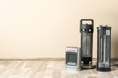 Photo of Different modern electric heaters on floor in room, space for text
