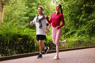 Photo of Happy couple running in park, low angle view. Morning exercise