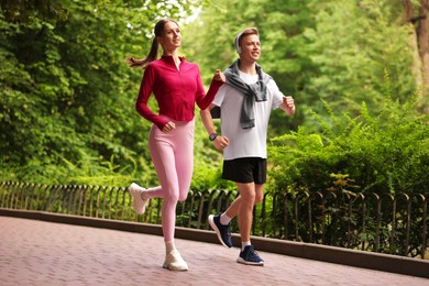Photo of Happy couple running in park, low angle view. Morning exercise