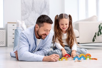 Photo of Father and his daughter playing with toys on warm floor at home. Heating system