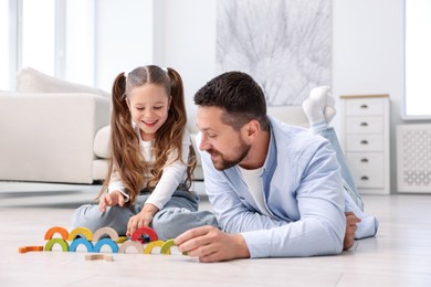 Photo of Father and his daughter playing with toys on warm floor at home. Heating system