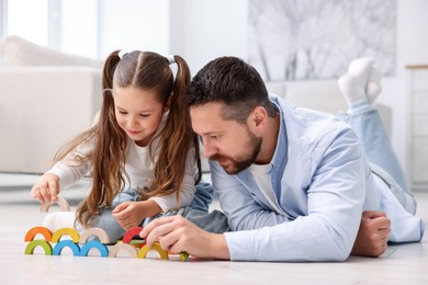Photo of Father and his daughter playing with toys on warm floor at home. Heating system