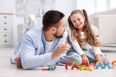 Photo of Father and his daughter playing with toys on warm floor at home. Heating system