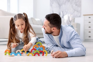 Photo of Father and his daughter playing with toys on warm floor at home. Heating system