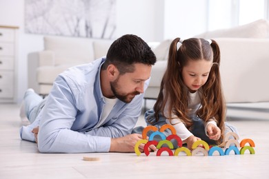 Photo of Father and his daughter playing with toys on warm floor at home. Heating system