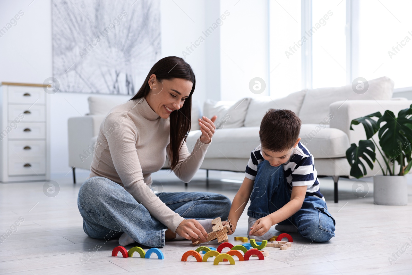 Mother and her son playing with toys on warm floor at home. Heating system Photo of Mother and her son playing with toys on warm floor at home. Heating system