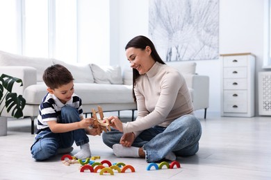 Photo of Mother and her son playing with toys on warm floor at home. Heating system