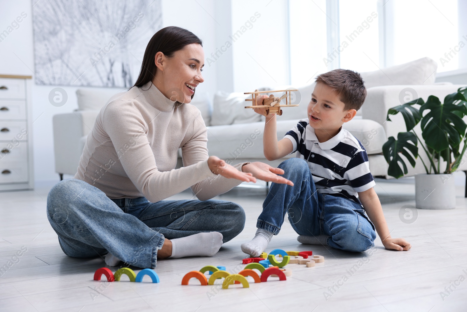 Mother and her son playing with toys on warm floor at home. Heating system Photo of Mother and her son playing with toys on warm floor at home. Heating system