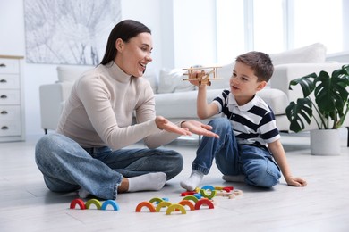 Photo of Mother and her son playing with toys on warm floor at home. Heating system
