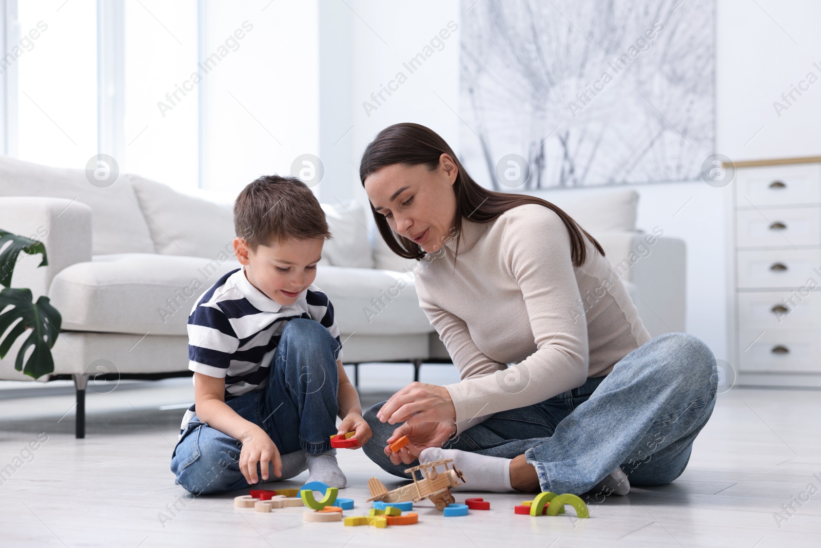 Mother and her son playing with toys on warm floor at home. Heating system Photo of Mother and her son playing with toys on warm floor at home. Heating system