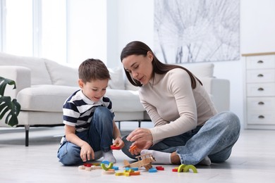 Photo of Mother and her son playing with toys on warm floor at home. Heating system