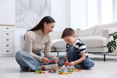 Photo of Mother and her son playing with toys on warm floor at home. Heating system
