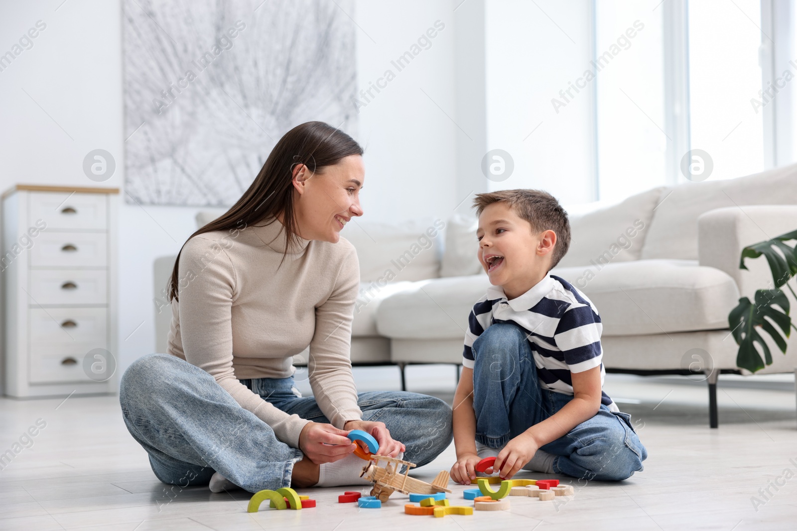 Photo of Mother and her son playing with toys on warm floor at home. Heating system