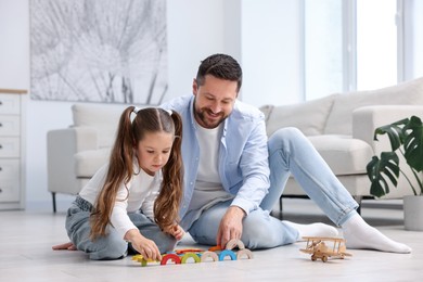 Photo of Father and his daughter playing with toys on warm floor at home. Heating system