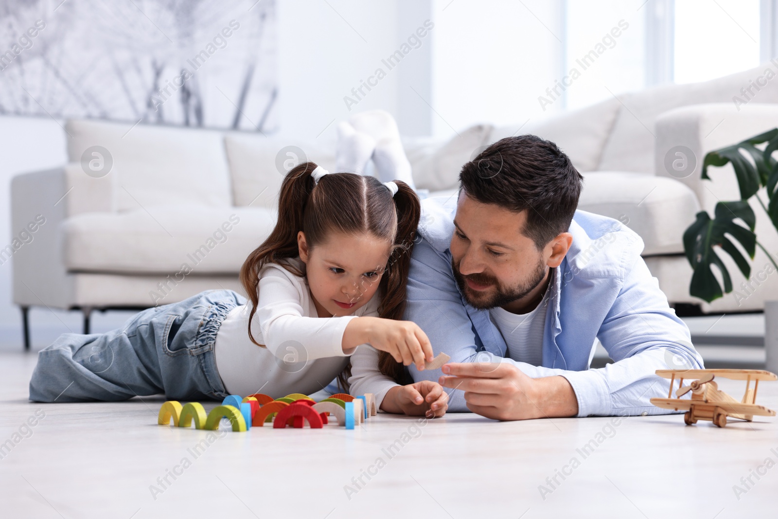 Father and his daughter playing with toys on warm floor at home. Heating system Photo of Father and his daughter playing with toys on warm floor at home. Heating system
