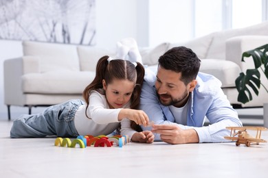 Photo of Father and his daughter playing with toys on warm floor at home. Heating system