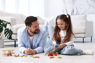 Photo of Father and his daughter playing with toys on warm floor at home. Heating system