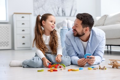 Photo of Father and his daughter playing with toys on warm floor at home. Heating system